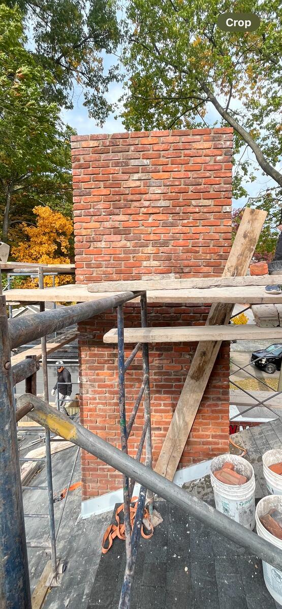 Mason inspecting chimney for damage assessment